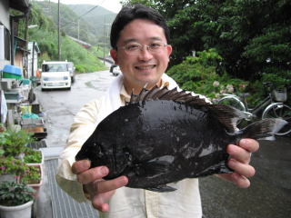 魚を掲げる井田氏